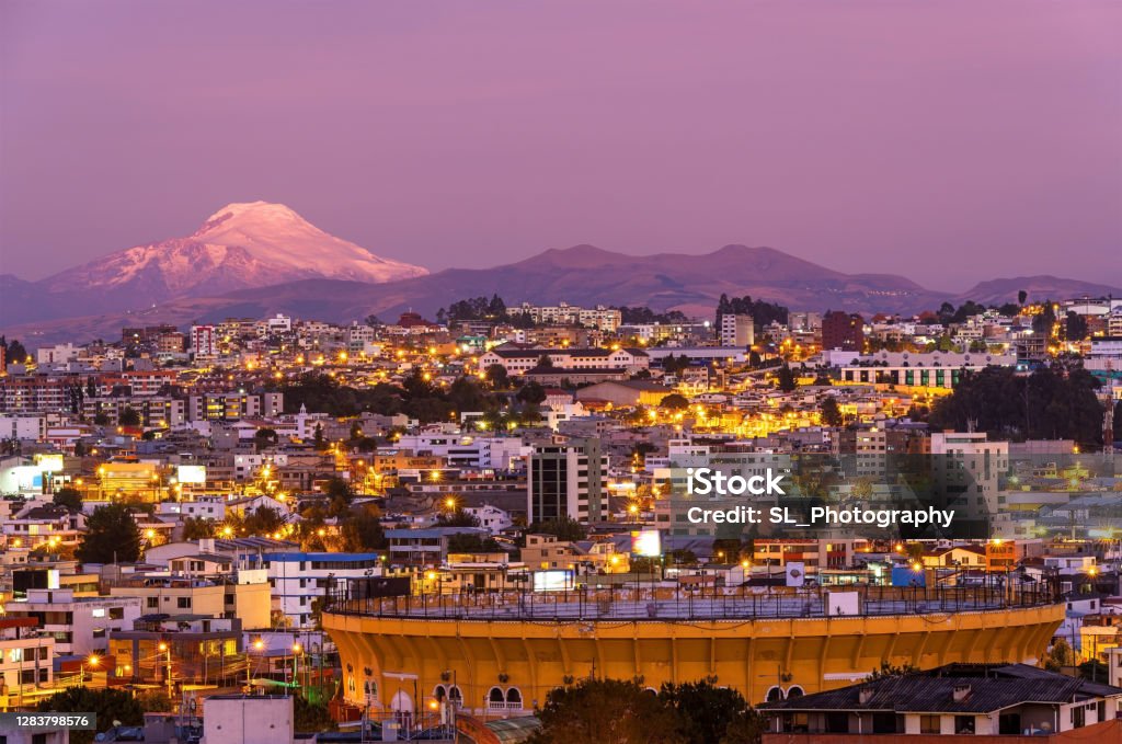 Bullfighting Arena and Cayambe Volcano, Quito, Ecuador The bullfighting arena of Quito city at night in a modern district with the Cayambe volcano, Ecuador. Quito Stock Photo