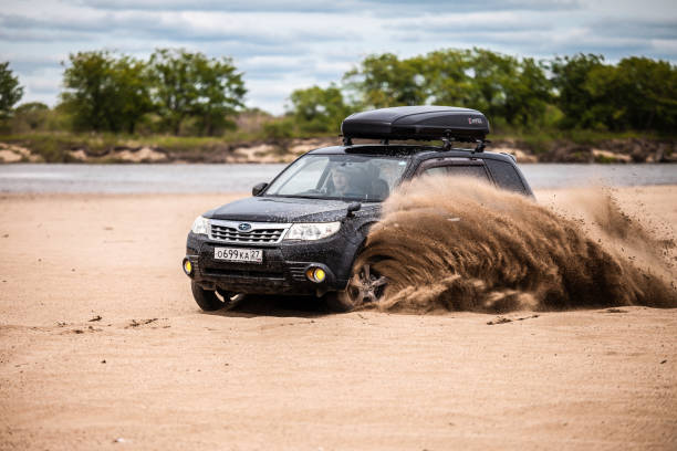 schwarzer subaru forester bewegt sich am sandstrand, sand fliegt unter den rädern - recreate stock-fotos und bilder