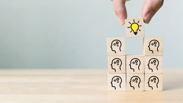 istock Concept creative idea and innovation. Hand picked wooden cube block with head human symbol and light bulb icon 1283801182