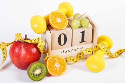 January 1 on cube calendar, fresh fruits, dumbbells and tape measure, new years resolutions of healthy lifestyle