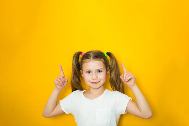 istock Beautiful child girl points fingers up. Copy space 1283805514