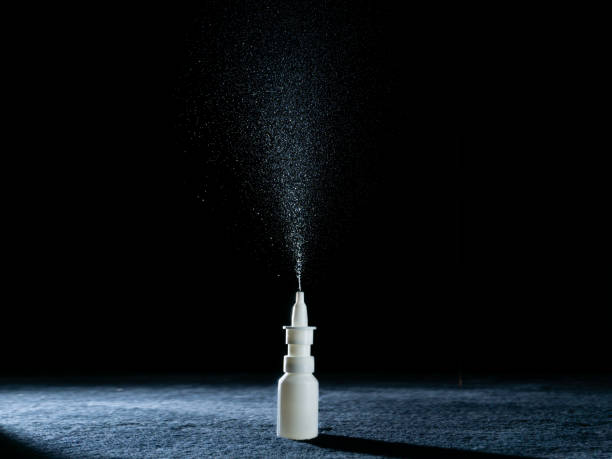 nasal spray with aerosol of spray spraying ehite nose spray bottle with black background and copy space nasal spray stock pictures, royalty-free photos & images
