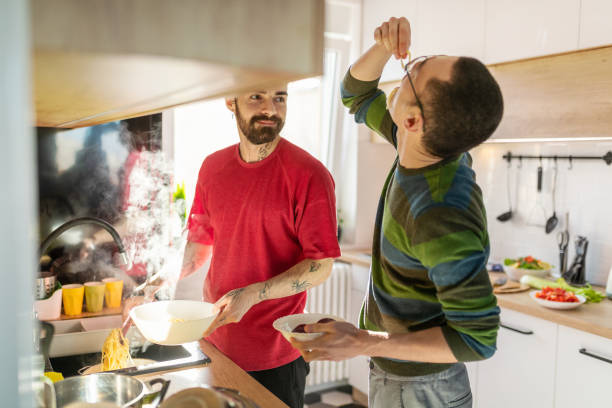 istock Gay couple testing hot drained spaghetti by the kitchen sink 1283813946