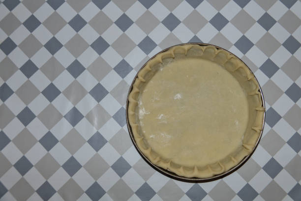 istock Top view of short crust pastry dough in baking dish at table. Preparation for pumpkin pie on Thanksgiving. Simple pie base. Copy space. Patterned background. Handmade. Man cooking. Dublin, Ireland 1283814824