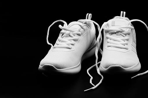 isolated a pair of brand new woman white sneakers on black background