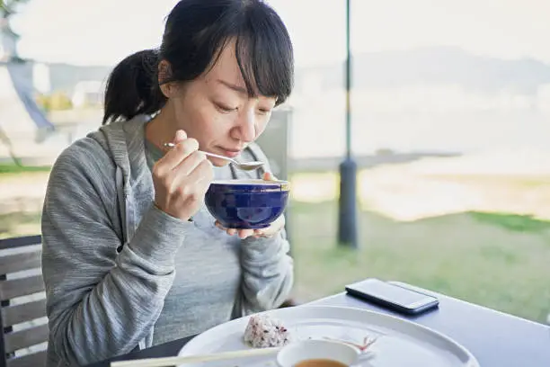 Japanese woman enjoys a vegan meal on the terrace of a vegan restaurant.