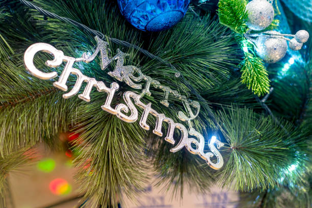 A Merry Christmas sign hangs on a decorated Christmas Tree. Closeup shot of a vinyl pine tree at a department store. A Merry Christmas sign hangs on a decorated Christmas Tree. Closeup shot of a vinyl pine tree at a department store. divisoria market stock pictures, royalty-free photos & images