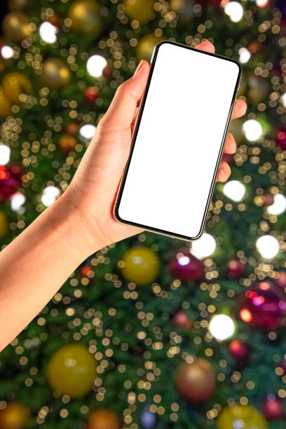 istock Close up hand holding phone isolated on white background with Illuminated  blurred bokeh of  Christmas tree decoration with  hanging lights ball. 1283822558