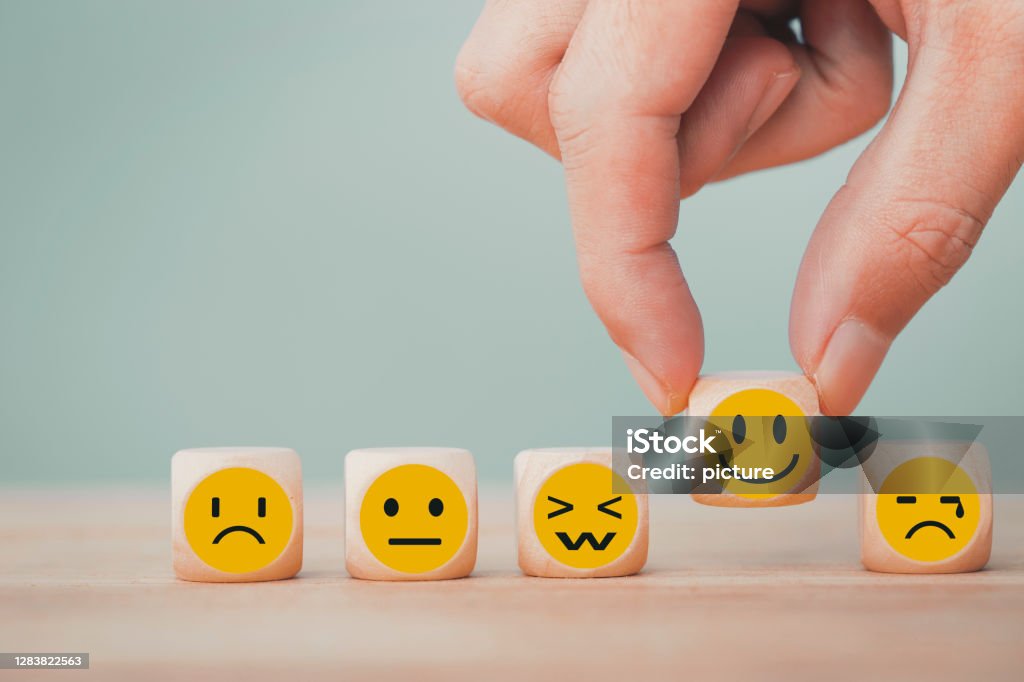 Hand chooses with happy smile face emoticon icons on Wooden Cube , good feedback rating for customer review survey Emotion Stock Photo