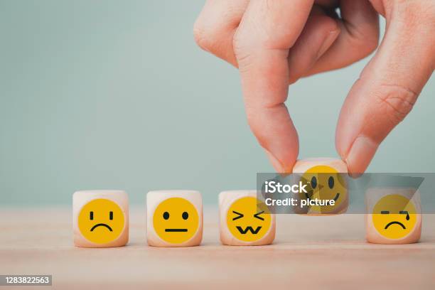 Hand Chooses With Happy Smile Face Emoticon Icons On Wooden Cube Good Feedback Rating For Customer Review Survey Stock Photo - Download Image Now