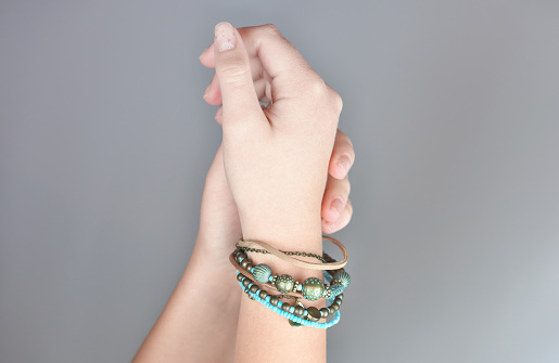 boho style bracelet made of leather and jems with metallic acsessories. blue and beige tones bracelet. modern stylish bijouterie. young woman hands. crop view.