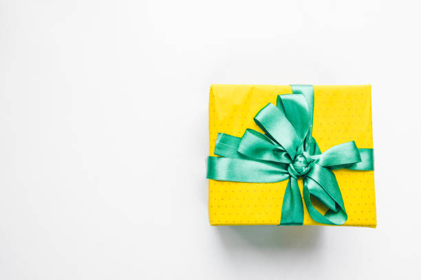 present gift box wrapped with yellow paper and blue ribbon top view