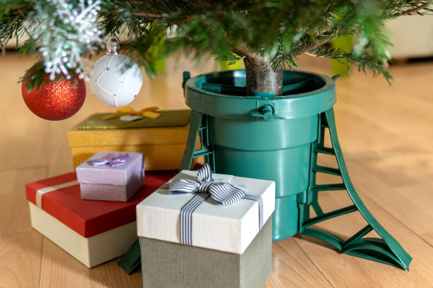 Gift boxes standing near a plastic Christmas tree stand at home in New Year eve stock photo