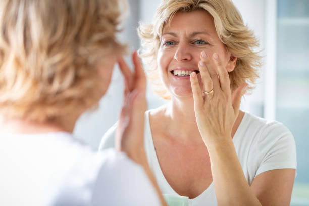 istock Blond woman's reflection in the mirror, smiling and touching her face 1283828952