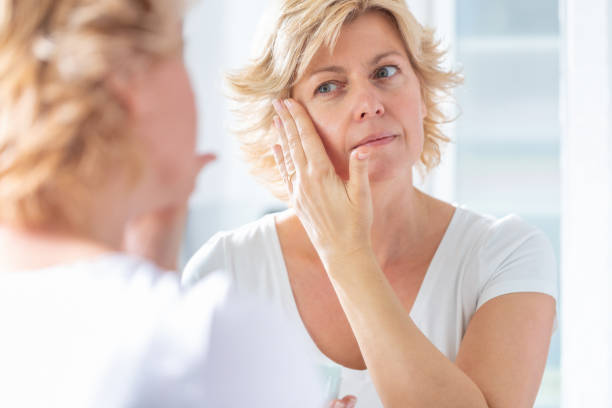 istock Blond woman's reflection in the mirror, massaging gently her face 1283828957