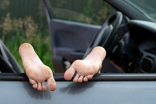 Schoolgirl's bare feet sticking out car window outdoors
