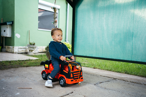 A toddler is enthusiastically playing with his toy car on his birthday