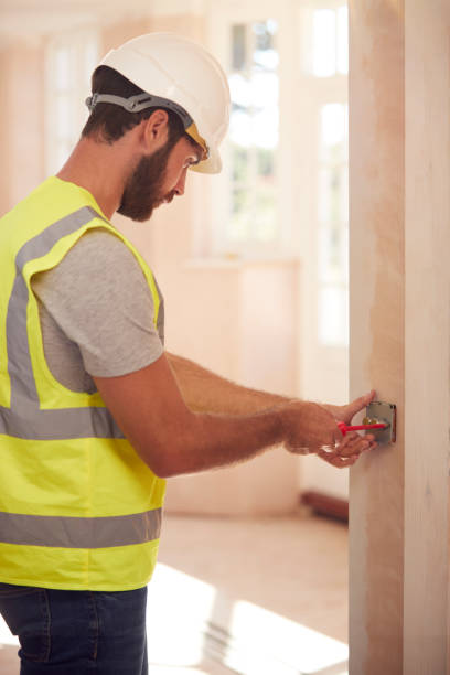 istock Electrician Wearing Hard Hat Fitting Light Switch At New Build Property 1283834361