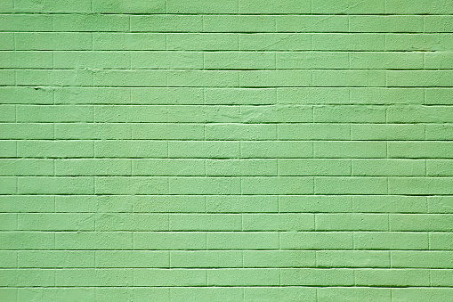 Concrete brick wall painted green color, suitable for construction or architecture background, horizontal view.