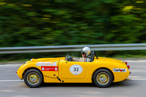 A modern yellow sports car speeding along a city street. Unique and generic sports car design.  Designed and modelled entirely by myself. Very high resolution 3D composite render. All markings are ficticious.