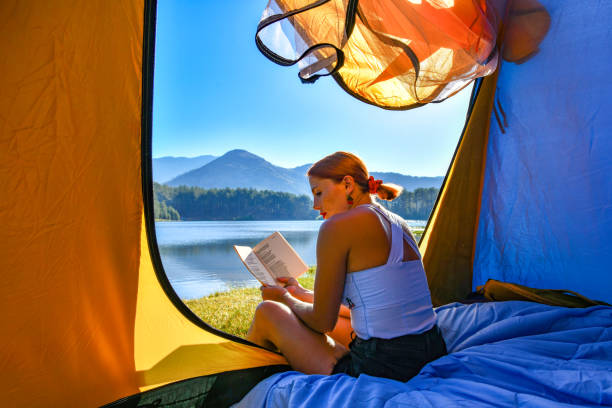 istock Woman reading a book in tent 1283840098