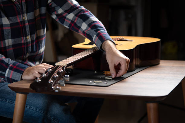 istock Man replacing strings on an acoustic guitar at home 1283841986