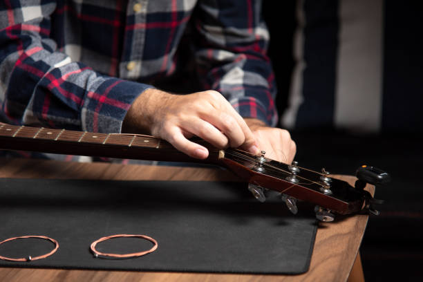 istock Man replacing strings on an acoustic guitar at home 1283841997