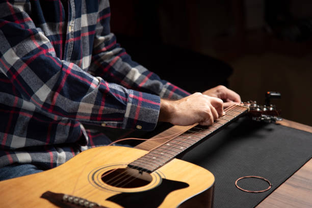 istock Man replacing strings on an acoustic guitar at home 1283842059