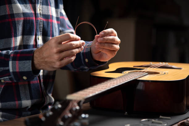 istock Man replacing strings on an acoustic guitar at home 1283842570