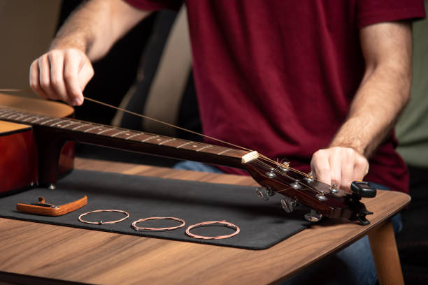 istock Man replacing strings on an acoustic guitar at home 1283842752