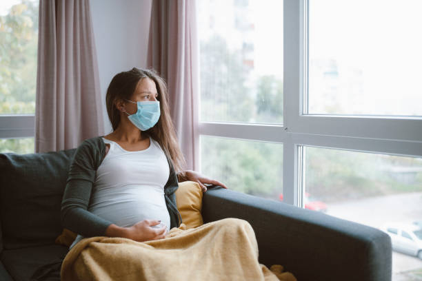 mujer embarazada preocupada con mascarilla protectora en casa. - anticipation built structure indoors image technique fotografías e imágenes de stock