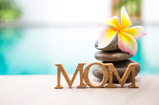 Mother's day concept background, tropical style nature with mom wooden text over blurred swimming pool water background, outdoor day light