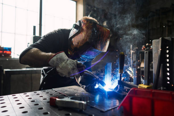 istock Focused welder with a protective workwear welding a metal frame with a welding torch 1283843416
