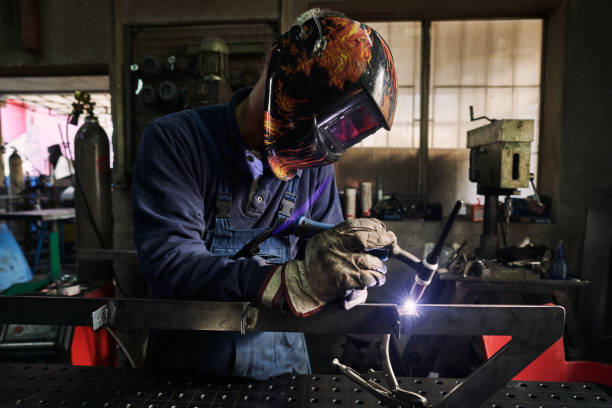 istock Professional welder wearing welding helmet while using a torch to connect metal pipes 1283843472