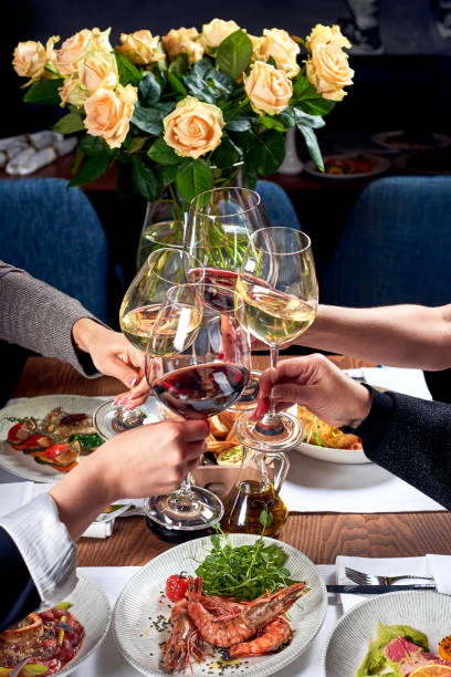istock Four hands with glasses of wine over a table with food. 1283844334