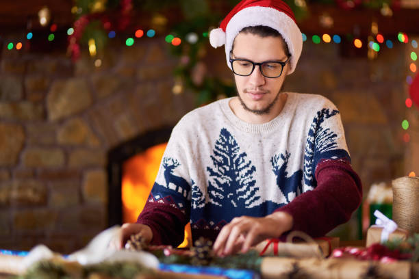 istock Happy man in a Santa hat creates gifts. 1283844483