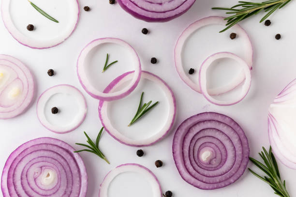 istock Background texture red onion Sliced into ring with black pepper and rosemary. Top view Garnish and food ingredients on isolated white background. 1283844490