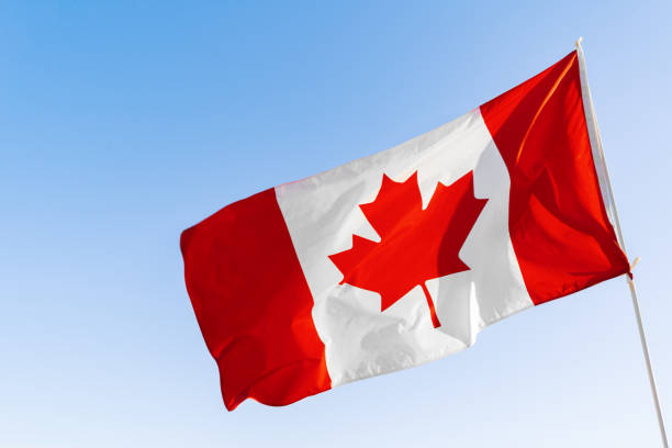 istock Flag of Canada waving against blue sky 1283845610