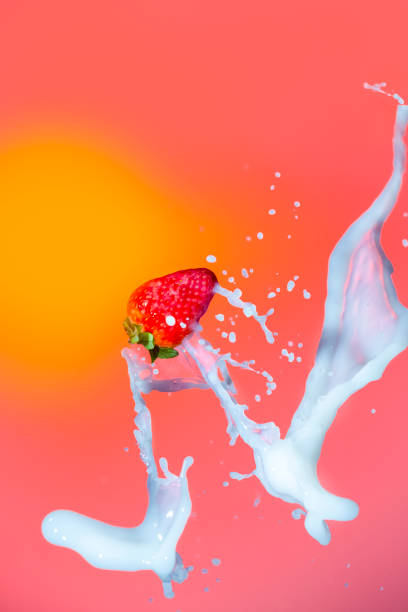 istock Splashes of Milk Around Strawberry Fruit. Against Red Background. Vertical Image Composition 1283845668