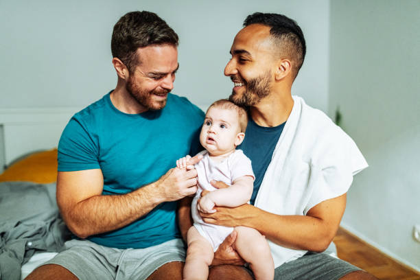 Smiling gay couple with adopted caucasian baby Gay couple adopted baby girl and enjoying the parenthood lgbtqia culture photos stock pictures, royalty-free photos & images