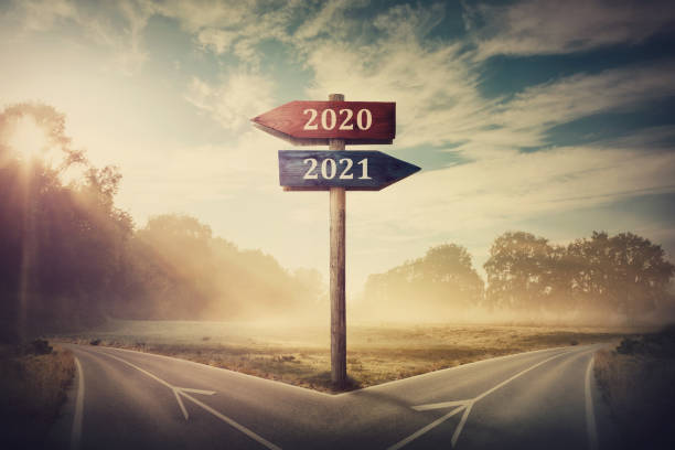 Surreal scene with a split road and signpost arrows showing two different courses, left and right, past and future, old 2020 and the new 2021 year direction to choose. Life decision, choice concept. escena surrealista con una carretera dividida y flechas de señalización que muestran dos campos diferentes, izquierda y derecha, pasado y futuro, viejo 2020 y la nueva dirección de 2021 años para elegir. decisión de vida, concepto de elección.