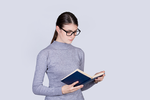 A young woman holds a notebook in her hands and standing against isolated white background