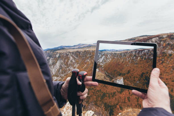 istock Man on a hiking photographs nature with a digital tablet 1283848608
