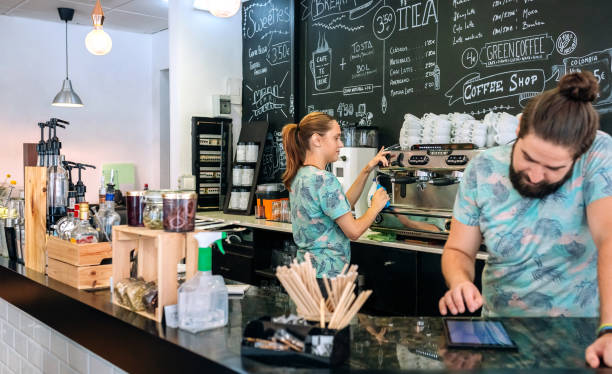 istock Waitress preparing coffee machine while her coworker uses the tablet 1283849875