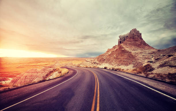 malerische wüstenstraße bei sonnenuntergang, usa. - badlands nationalpark stock-fotos und bilder