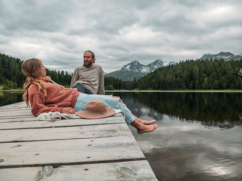 Two people by the lake looking at beautiful mountain landscape. Man and woman enjoying the outdoors