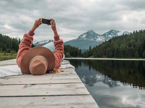One person on wooden lake pier relaxing and enjoying mountain lake scenery