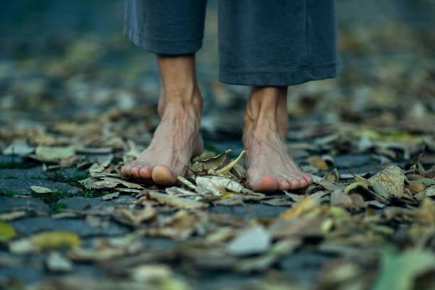 istock Feet close-up stands barefoot on autumn foliage. 1283851536