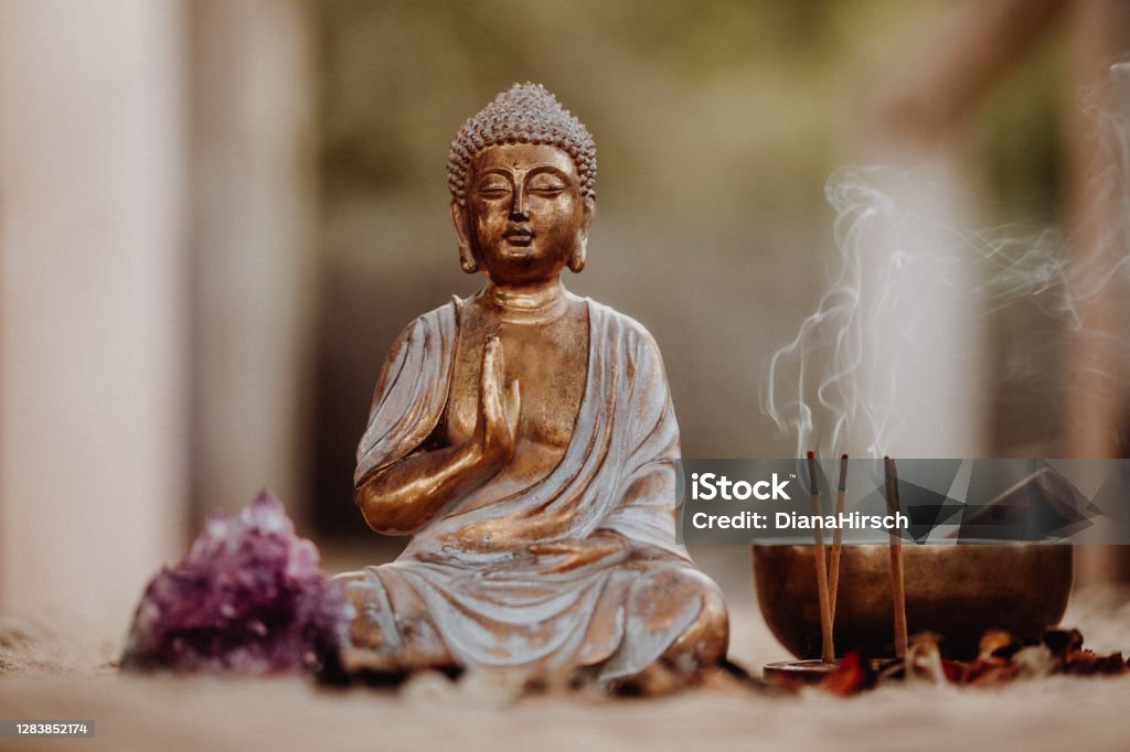 Close up of a Buddha figurine and smoky incense with gong and amethyst Close up of a Buddha figurine and smoky incense with gong and amethyst. Focus on the Buddha and the incense. Buddha Stock Photo