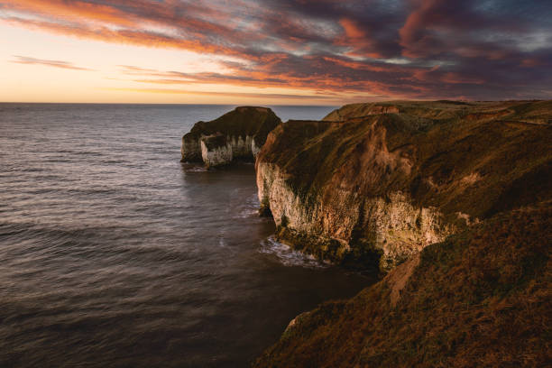 istock Sunrise over sea and eroded chalk cliffs under bright sky along coastline. Flamborough, UK. 1283852472
